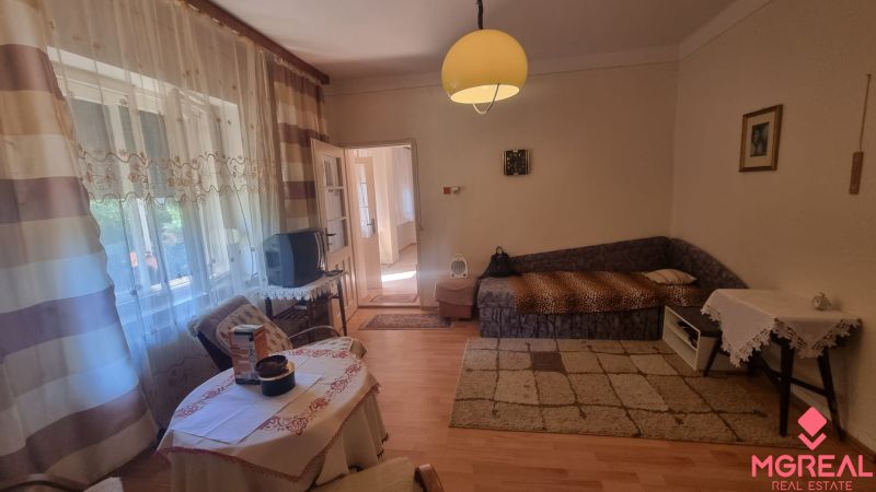 Living room in a family house with a carpet and large windows, floor with wooden decor.