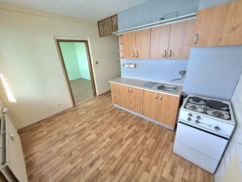 Kitchen unit and stove in a studio apartment with a wooden decor floor.
