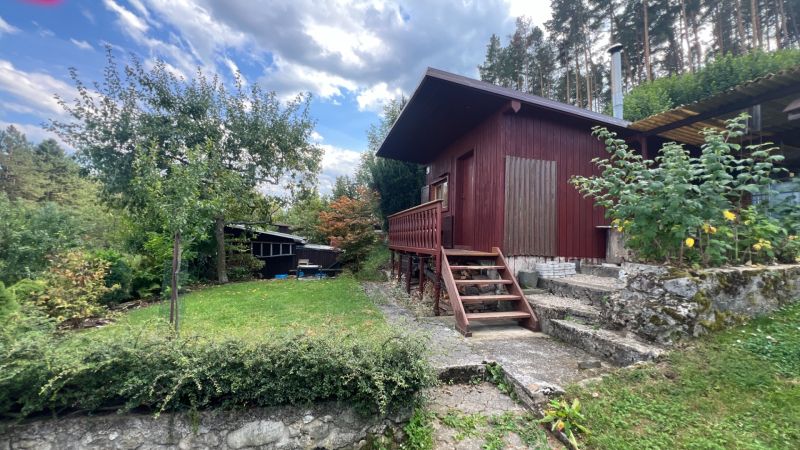 A wooden cabin surrounded by greenery in the Gardens near Ružomberok with stone-clad steps.
