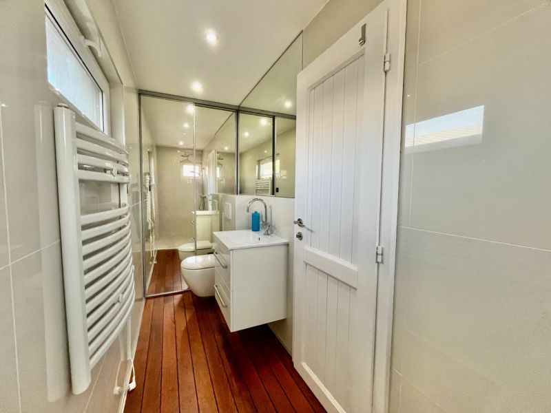 A bathroom with a mirror, sink, radiator, and floor with a wooden decor in Záhrady.