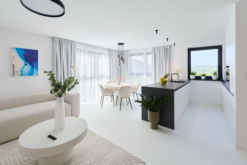 Bright living room with a kitchen in a 4-room apartment, large windows and curtains.