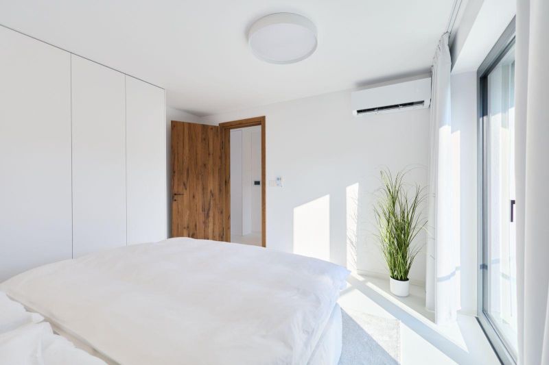 Bright bedroom in a 4-room apartment with a bed, plant, and white cabinets.