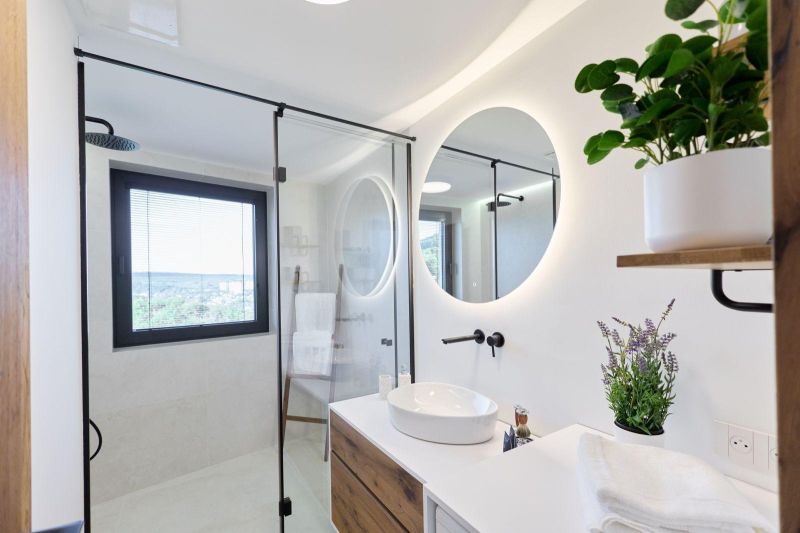 A bathroom in a 4-room apartment with an illuminated round mirror and plants.