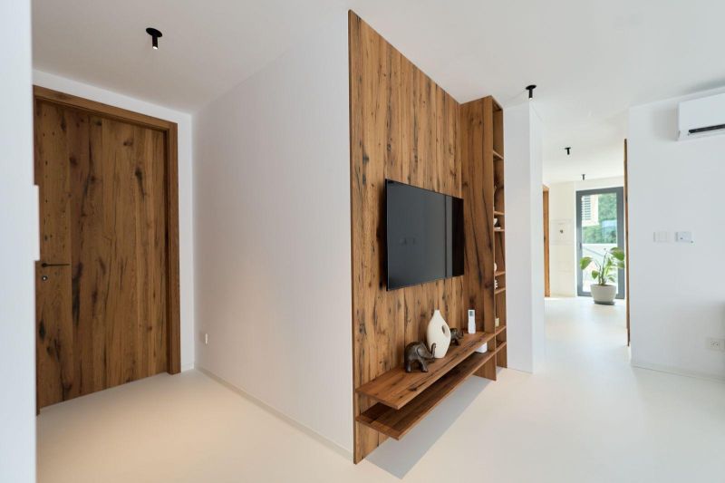 Interior of a 4-room apartment with a TV on the wall and a floor with a wooden decor.