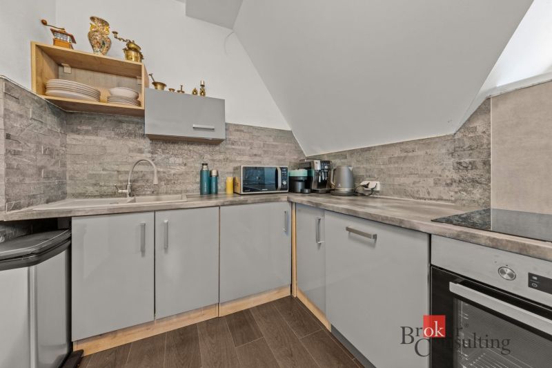 A kitchen in a 4-room apartment with a stone-clad wall and a floor with a wooden decor.