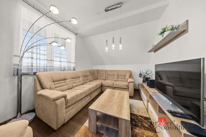 Living room with a sofa, TV, lighting fixtures, and a floor with a wood decor in a 4-room apartment.