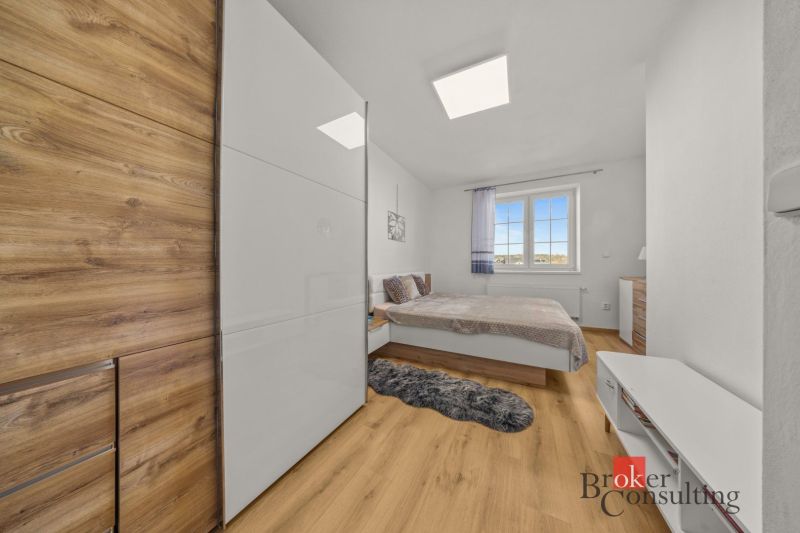 Bedroom in a 4-room apartment with wood-patterned flooring, wardrobe, and bed.