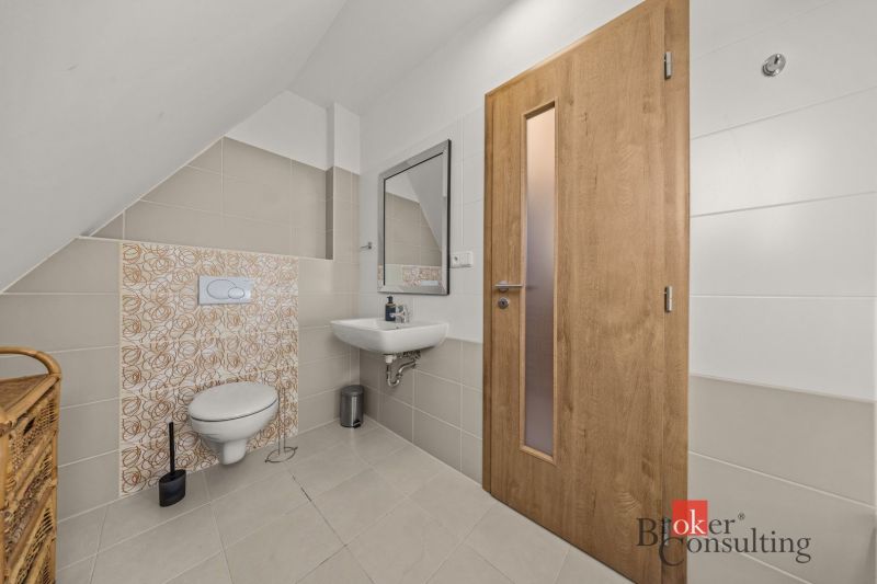 Bathroom with a wall-mounted toilet, sink, and wooden door in a 4-room apartment.