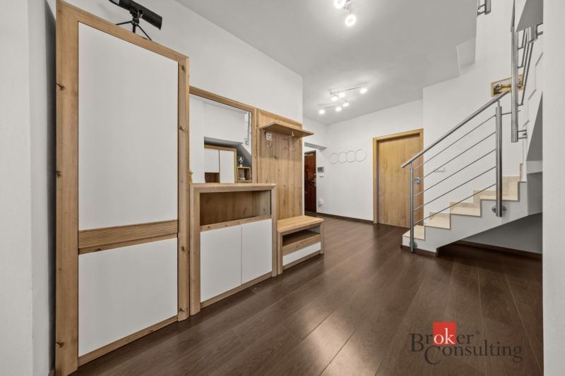 A hallway in a 4-room apartment with a wooden decor floor and a staircase.