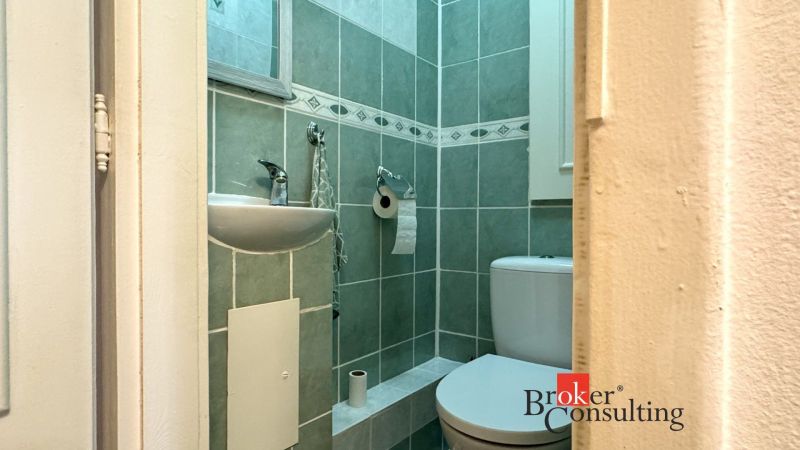 A bathroom with a sink and green tiles in a 3-room apartment.