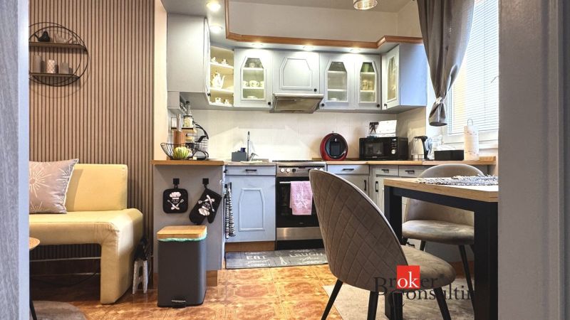 A kitchen in a 3-room apartment with a wooden decor floor and grey cabinets.