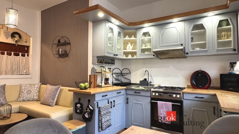 A kitchen in a 3-room apartment with a corner unit and decorative shelves.