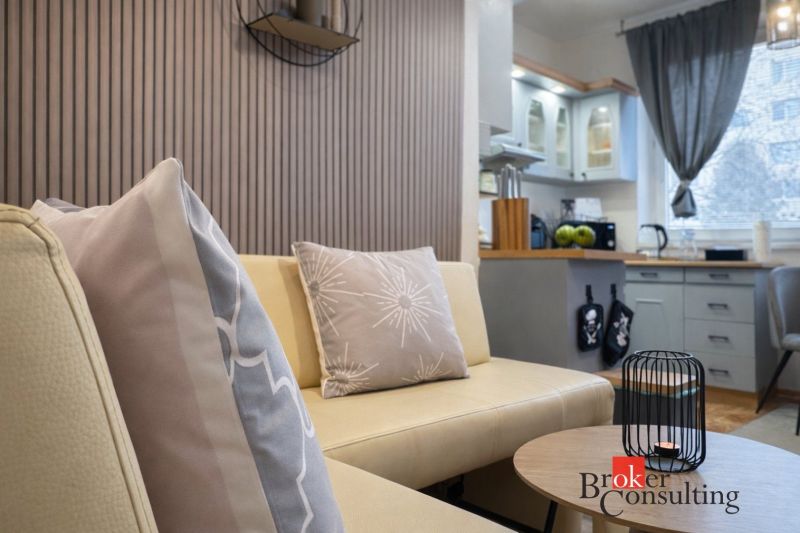 Interior of a 3-room apartment with a beige sofa and a kitchen in the background.