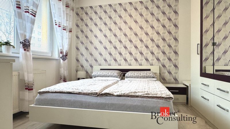 A bedroom in a 3-room apartment with elegant wallpaper and patterned curtains.