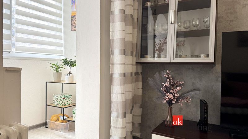 Interior of a 3-room apartment with flowers, a shelf, and decorations on the shelf by the window.