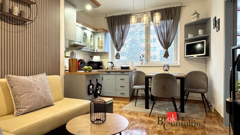 A kitchen in a 3-room apartment with stylish lighting fixtures and a wooden decor floor.