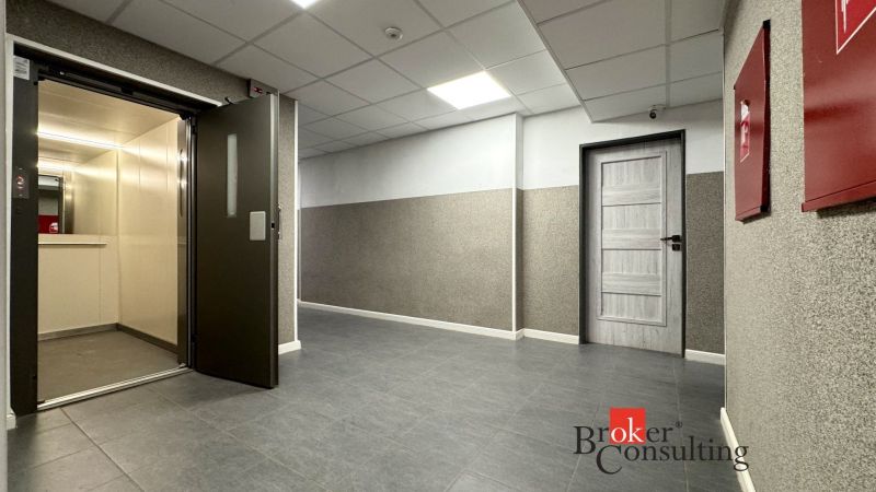 A hallway with gray tiles, an elevator, and doors in a 3-room apartment.