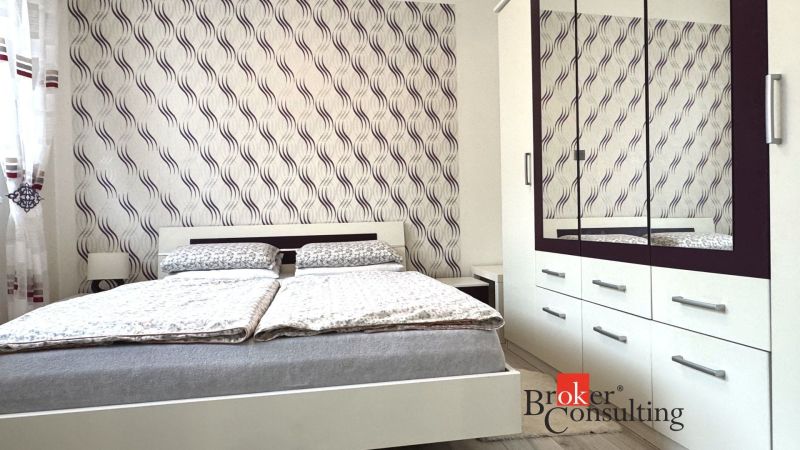 A bedroom in a 3-room apartment with a bed and a wardrobe, patterned wallpaper on the wall.