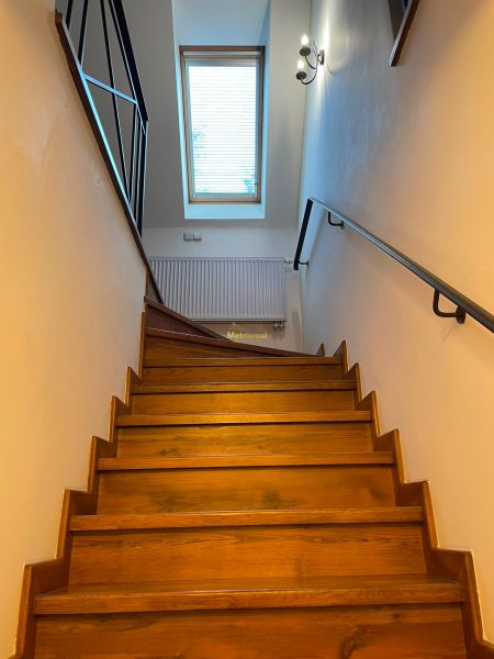 A staircase with wooden decor, a skylight, and a railing in a family house.