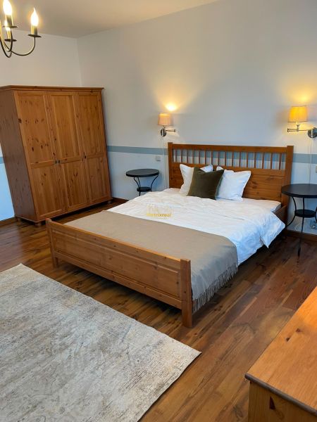 A bedroom with wooden furniture, a floor with a wooden decor, and a carpet in a family house.