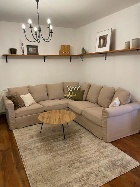 Living room of a family house with a sofa, coffee table, and wooden decor flooring.