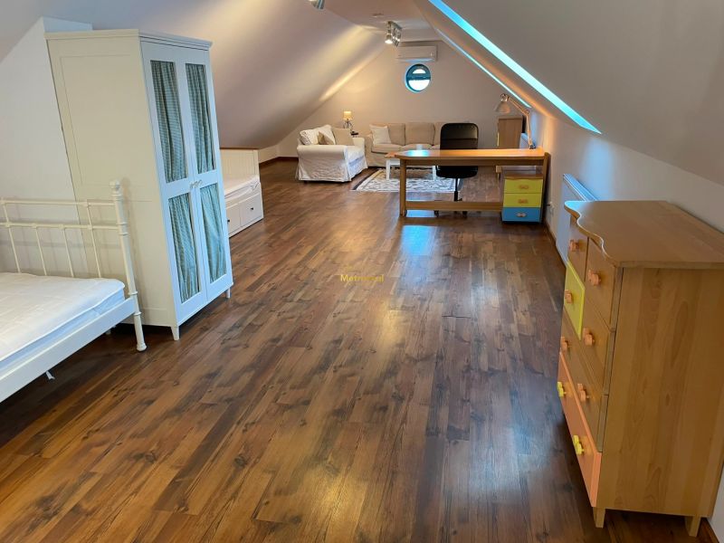 Attic room with wooden decor, sofa, table, and bed in a family house.