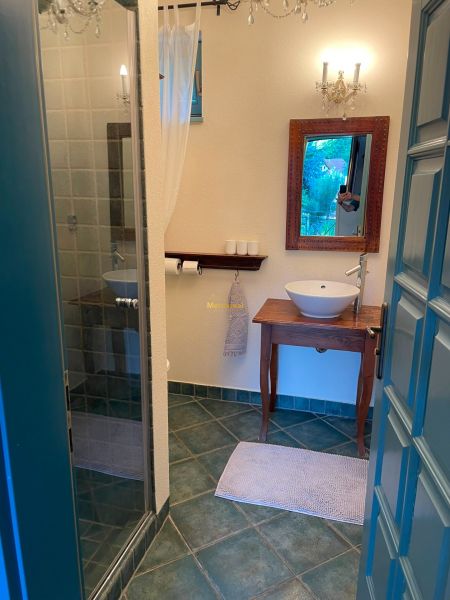 A bathroom with a sink on a wooden table and a shower corner.