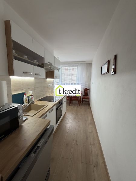 A kitchen in a 2-room apartment with a wooden decor floor and a dining table.