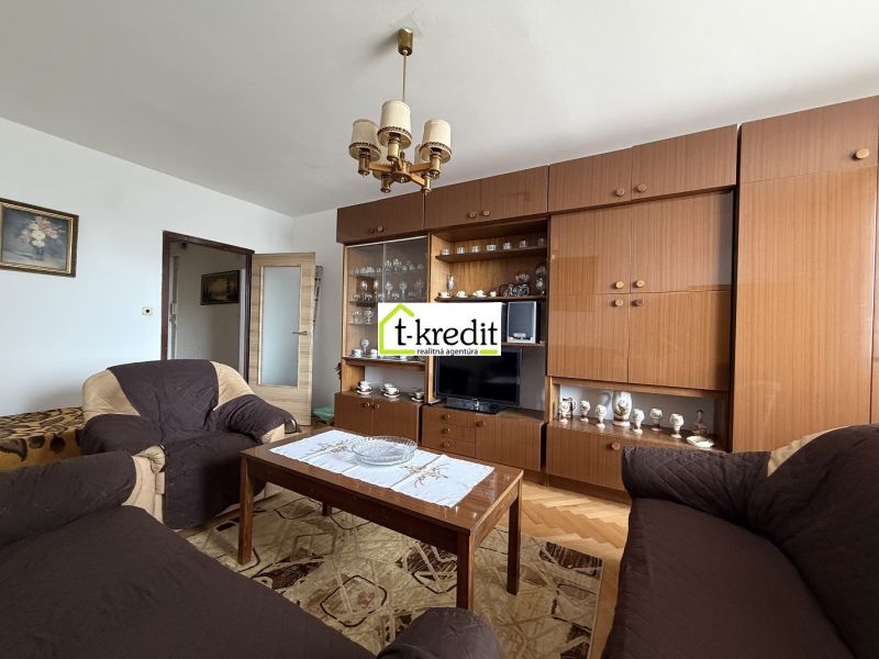 Living room in a two-room apartment with wooden decor furniture and a chandelier.