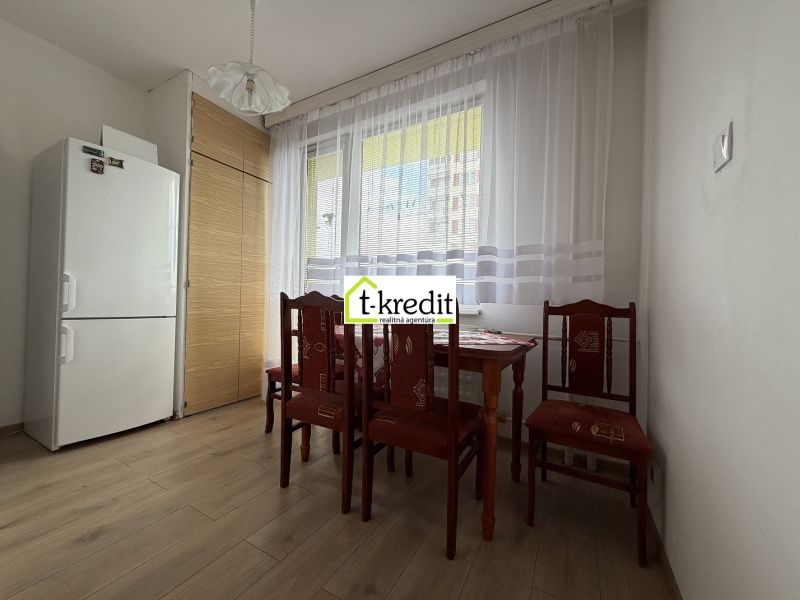 Dining area in a 2-room apartment with wood-patterned flooring and a white refrigerator.