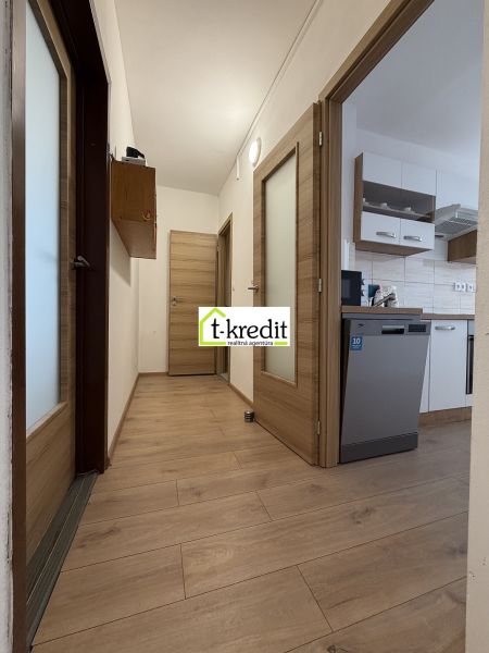Hallway of a 2-room apartment with a kitchen, white walls, and a floor with a wooden decor.