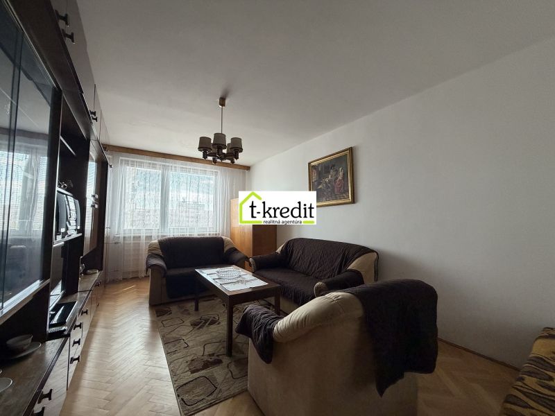 Living room with a sofa, carpet, and wood-patterned flooring in a 2-room apartment.