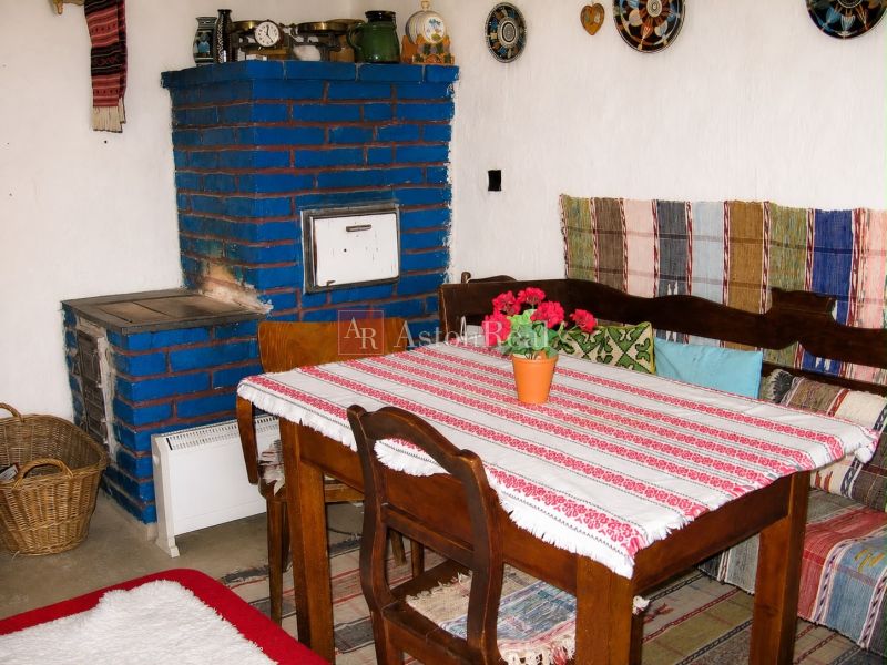 A traditional cottage with a blue stove and wooden furniture, colorful textiles.