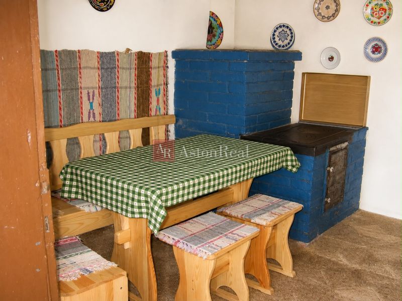 Corner bench with table, blue stove, decorative plates on the wall.