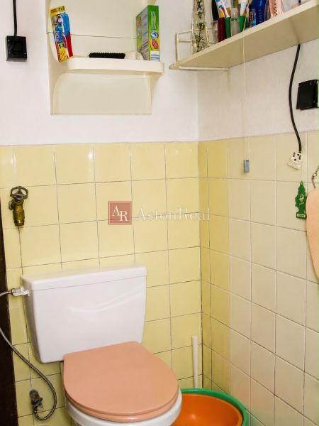 A bathroom in a cottage with beige tiles and shelves for necessities.