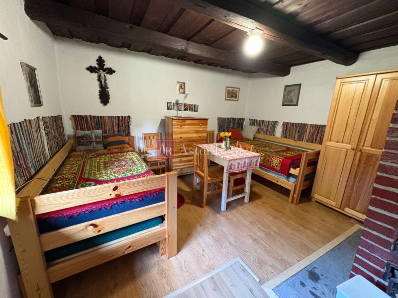 Traditional room in a cottage with beds, wooden furniture, and a floor with a wooden decor.
