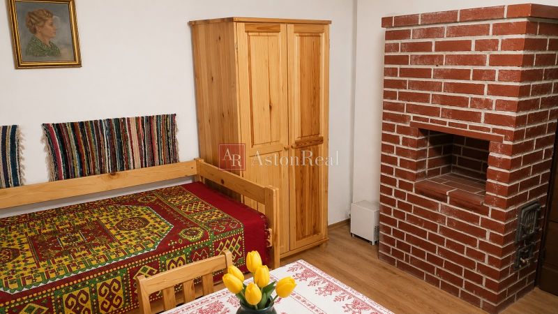 Traditional cottage with a bed, brick fireplace, and wooden furniture.
