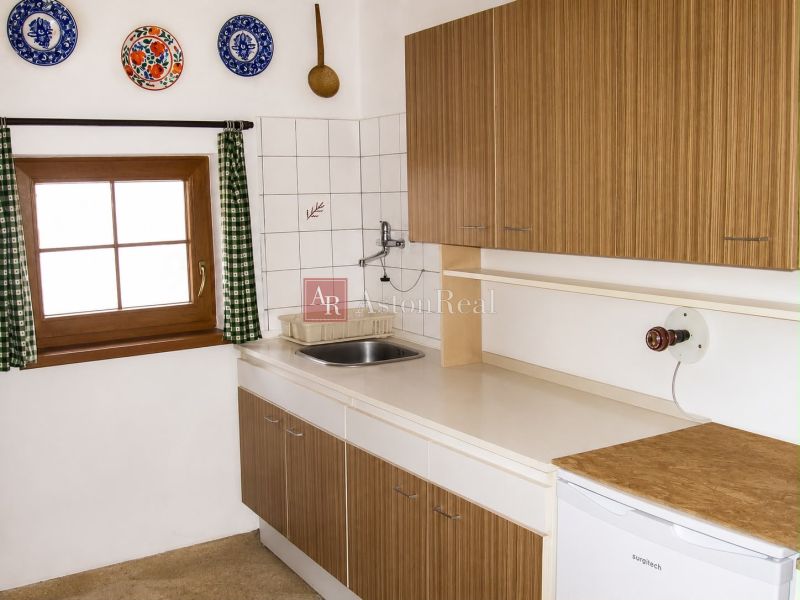 A kitchen in a cottage with wooden decor and colorful dishes on the wall.