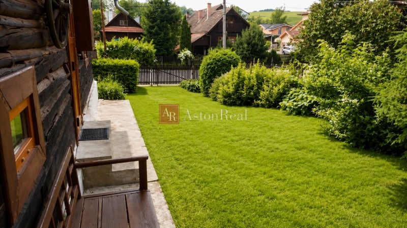 The garden of the cottage in Beňadiková with a lawn and wooden structures in the background.