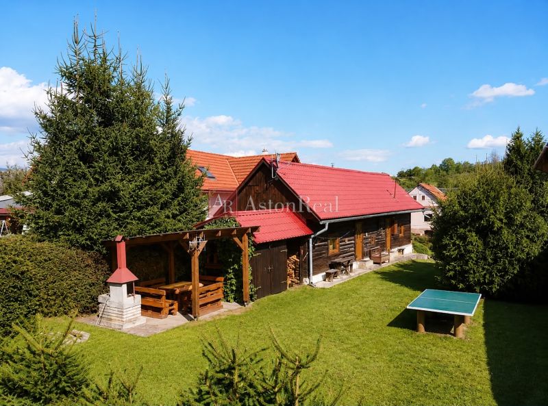 A wooden cottage in Beňadiková with a terrace and a garden table on a grassy area.