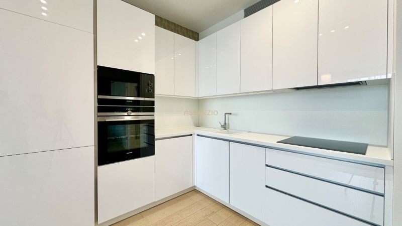 White kitchen with built-in appliances and glossy cabinets in a 2-room apartment.