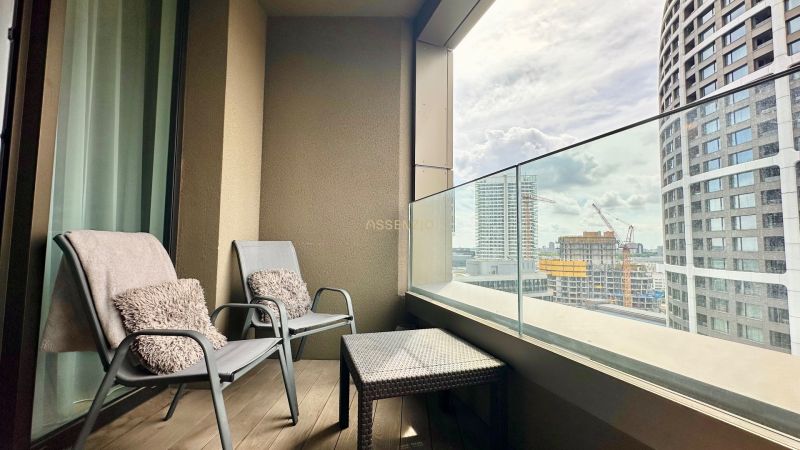 A balcony of a 2-room apartment with two chairs and a view of the city.