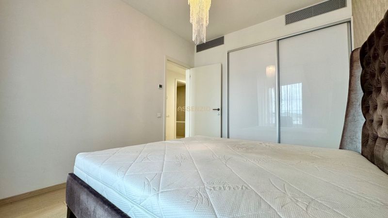 A bedroom with a bed, a white wardrobe, and a light fixture in a 2-room apartment.