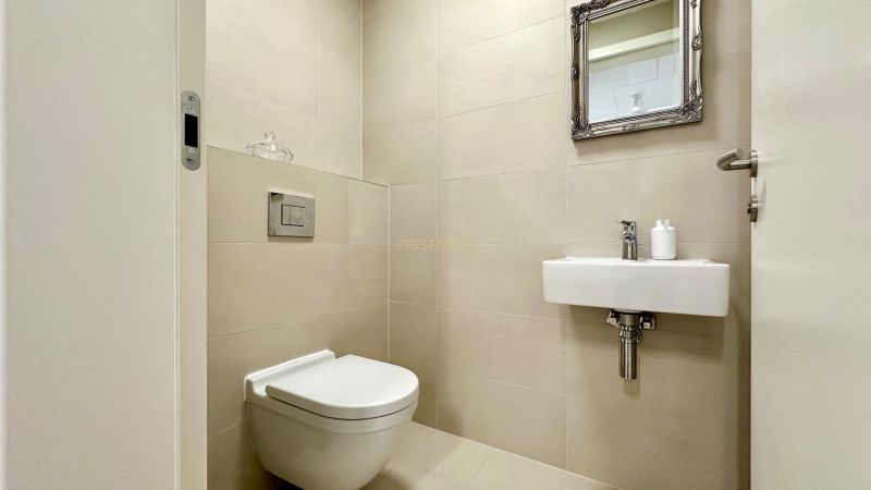 A toilet with a simple sink and mirror in a 2-room apartment.