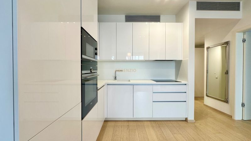 A kitchen with built-in appliances and a wooden decor floor in a 2-room apartment.