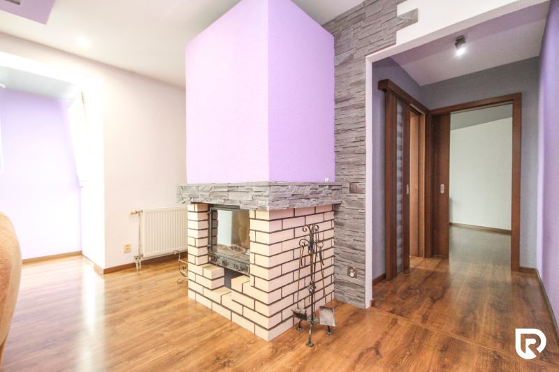 Interior of a family house with a fireplace, purple walls, and a wood-patterned floor.