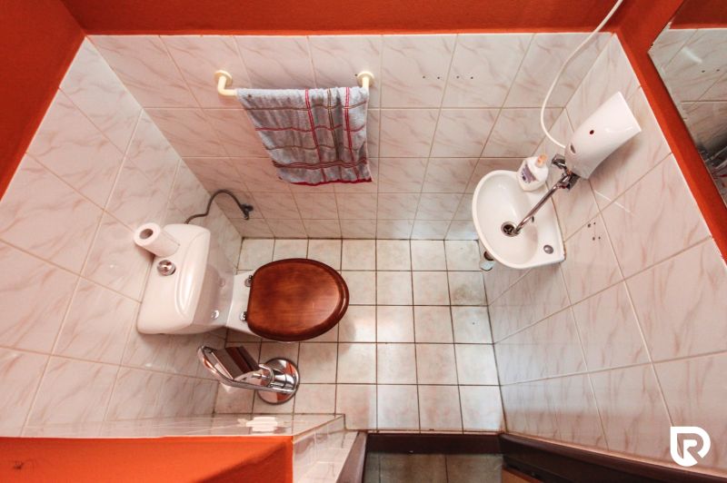 Bathroom in a family house with tiles, a toilet, and a small sink.