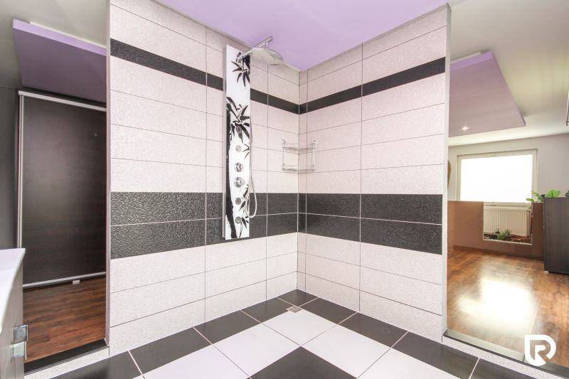A shower corner with modern tiles and a wooden decor floor in a family house.