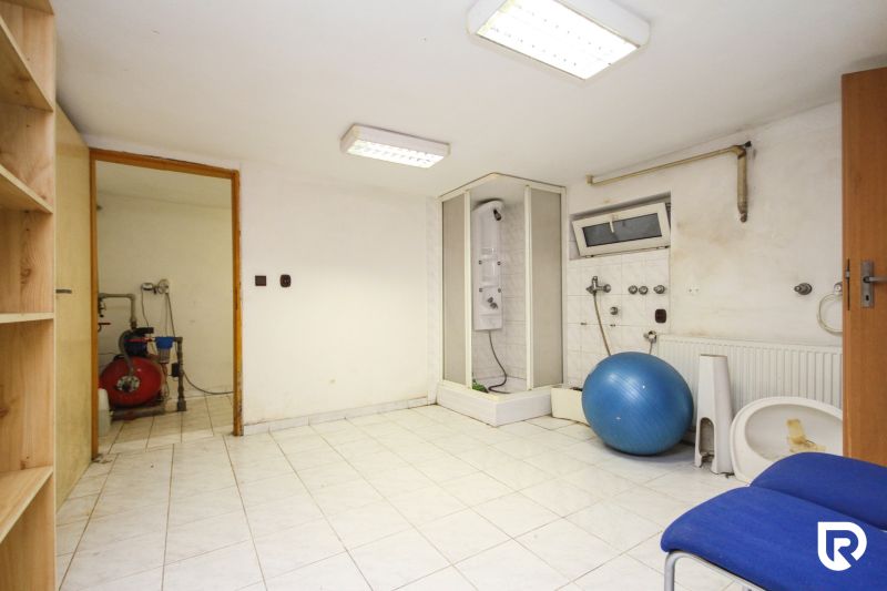 A bathroom in a family house with a shower, an exercise ball, shelves, and tiles.