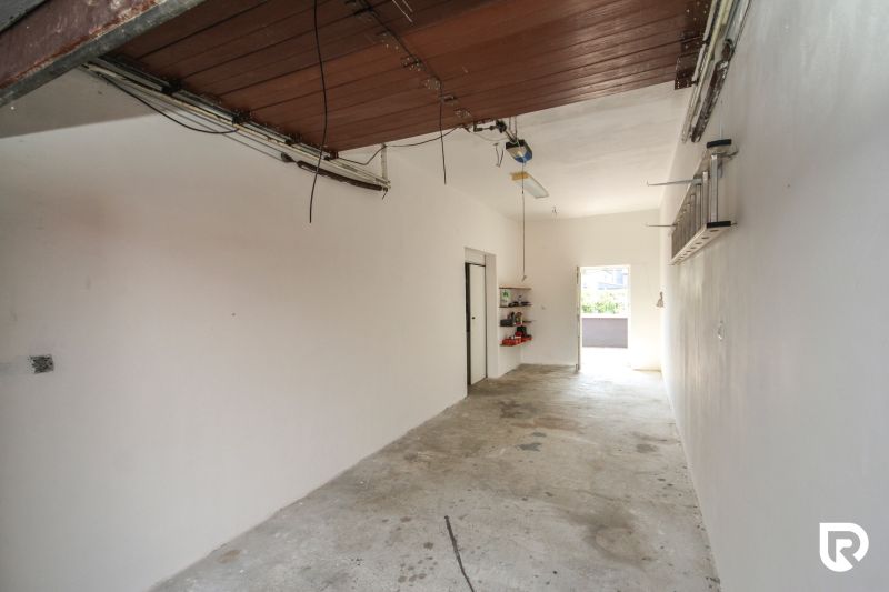 The interior of a garage in a family house with open doors and practical shelves.